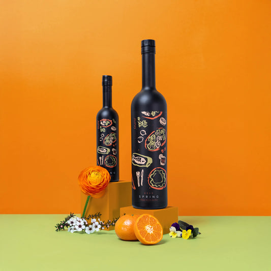 Two bottles of Spring 2025 Seasonal Gin against an orange background