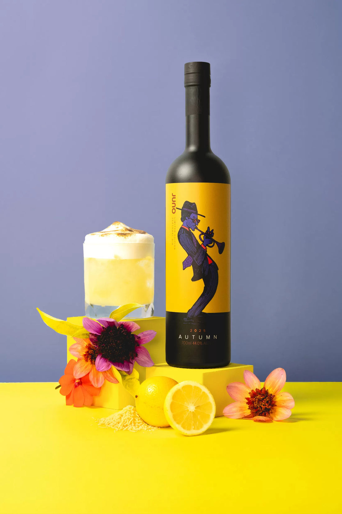 A meringue-topped Cloud Nine cocktail next to a bottle of Juno Autumn 2025 Seasonal Gin and flowers 