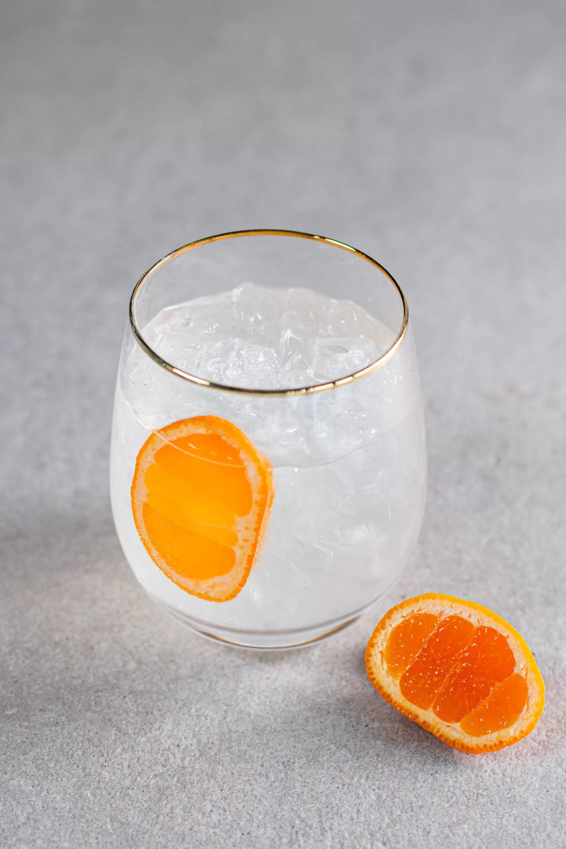 An Electric Storm cocktail in a gold-rimmed glass with mandarin garnish