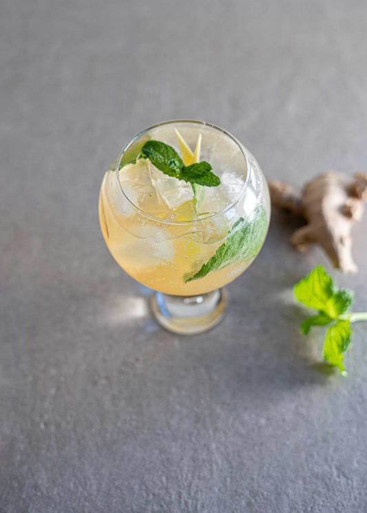 An Off the Beaten Track cocktail in a round glass with ginger and mint garnish