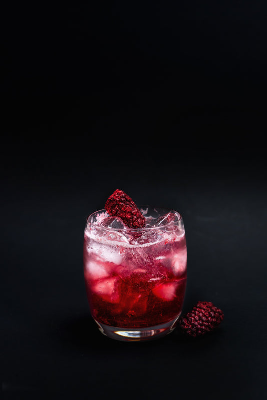 A Dark Frost cocktail with boysenberry garnish on a black background