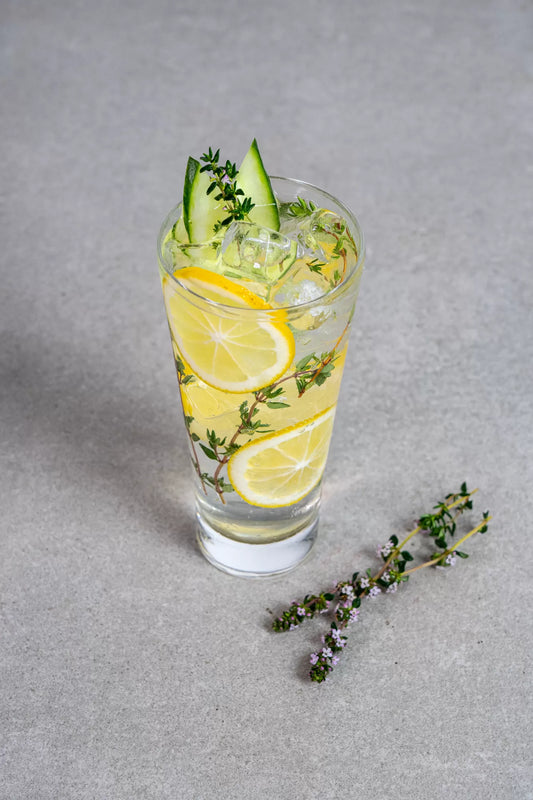 A tall Fiddler's Green cocktail with cucumber lemon and thyme garnish