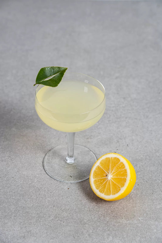 A yellow Lemon Drop cocktail in a coupe glass with a lemon leaf garnish