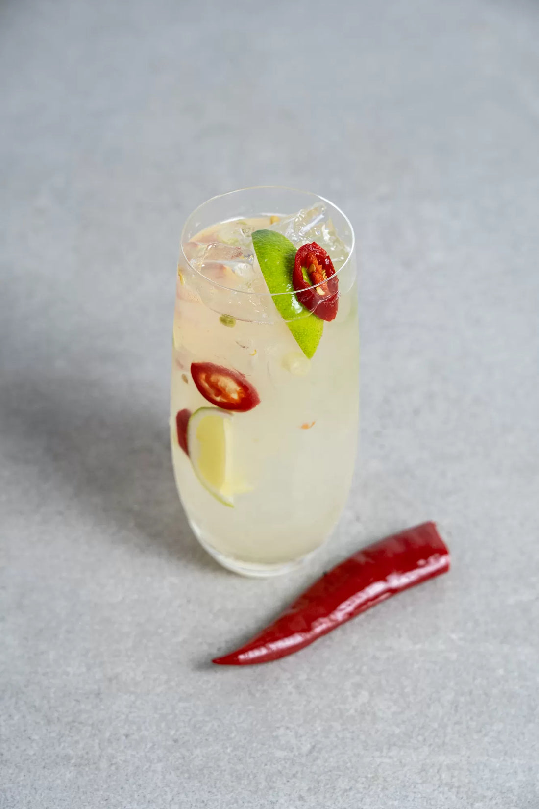A tall Tom Yum cocktail with lime and chilli slice garnish