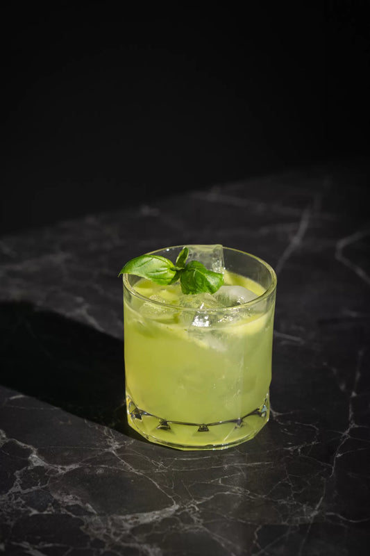 A smashed basil cocktail in a rocks glass with a basil garnish