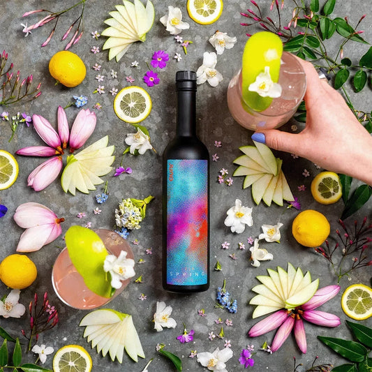 A bottle of Spring 2024 Seasonal Gin with apple slices and flowers